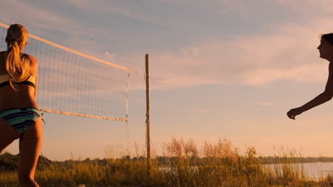 Beach-volleyball-match-girls-hit-the-ball-in-slow-motion-at-sunset-on-the-sand